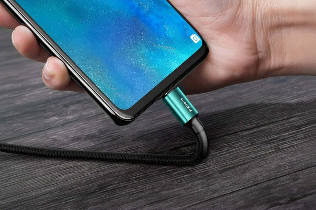 Hand connecting Baseus 100W USB-C fast charging cable to smartphone for quick charging and data transfer.